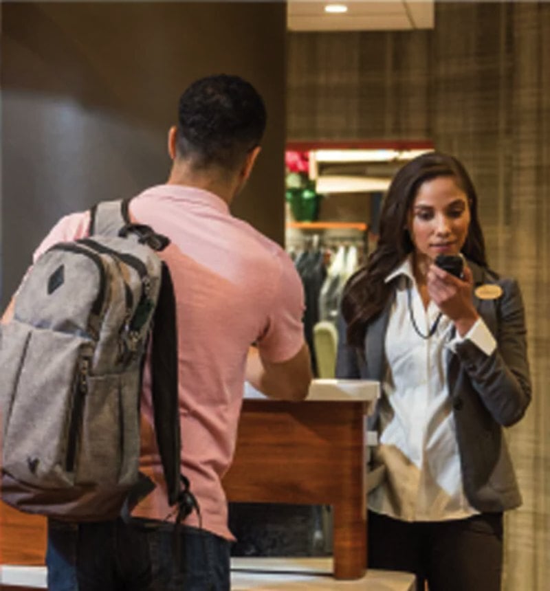 Recepcionista de hotel atendendo hóspede com dispositivo Zebra